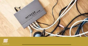 A switch with various network cables tangled on a wooden surface for Subnetting, branded with the NetworkUstad logo