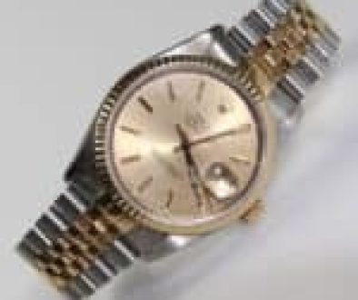 A luxury wristwatch with a gold and silver band, featuring a gold dial and date display.