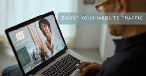 Person looking at a laptop screen with text ‘BOOST YOUR WEBSITE TRAFFIC’ indicating strategies for improving online visitor numbers.