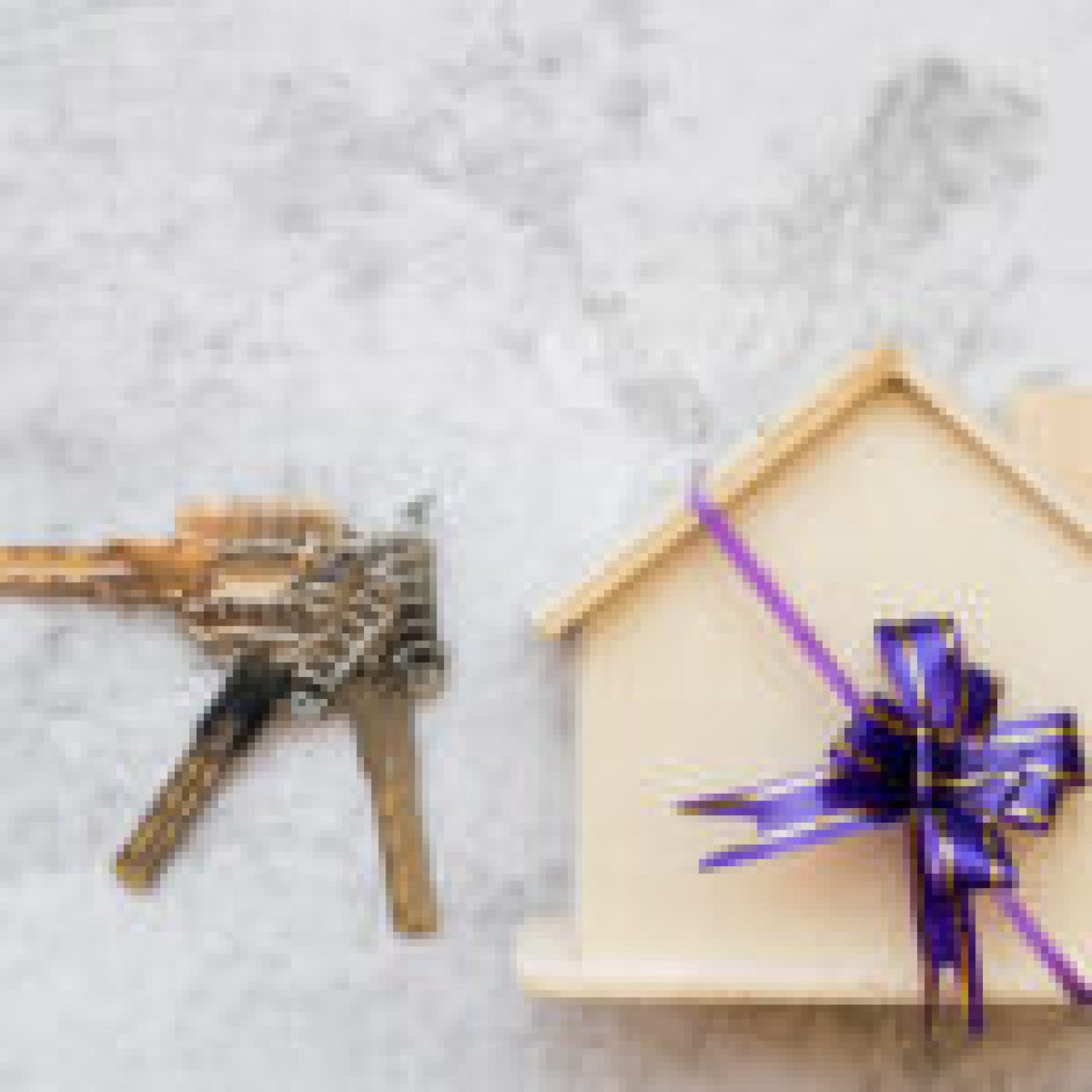 silver-keys-near-house-wooden-model-with-ribbon-bow-white-concrete-wall