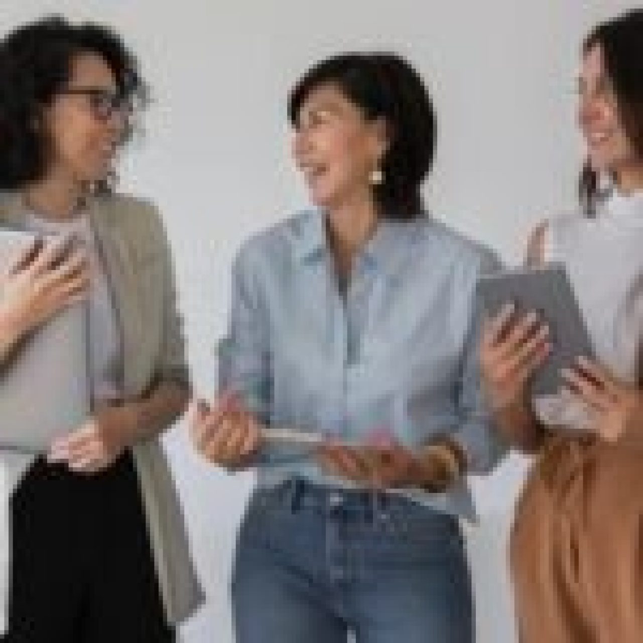 Three individuals standing together, holding electronic devices and discussing something. #Top 10 Languages That are Hardest to Learn