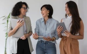 Three individuals standing together, holding electronic devices and discussing something. #Top 10 Languages That are Hardest to Learn