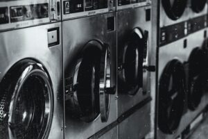 Row of modern semi-automatic washing machines in grayscale.