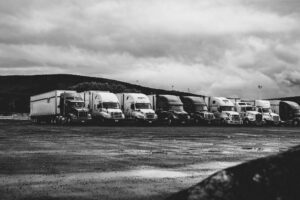 A monochrome photo of multiple trucks parked at a rest area under an overcast sky, symbolizing road safety through vehicle technology.