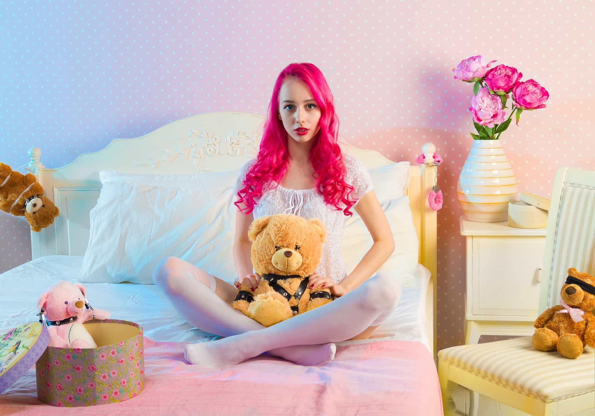 A child holding a teddy bear with a big smile, surrounded by other teddy bears and colorful decorations.