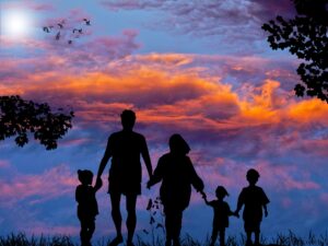 Silhouette of a family holding hands against a vibrant sunset sky.
