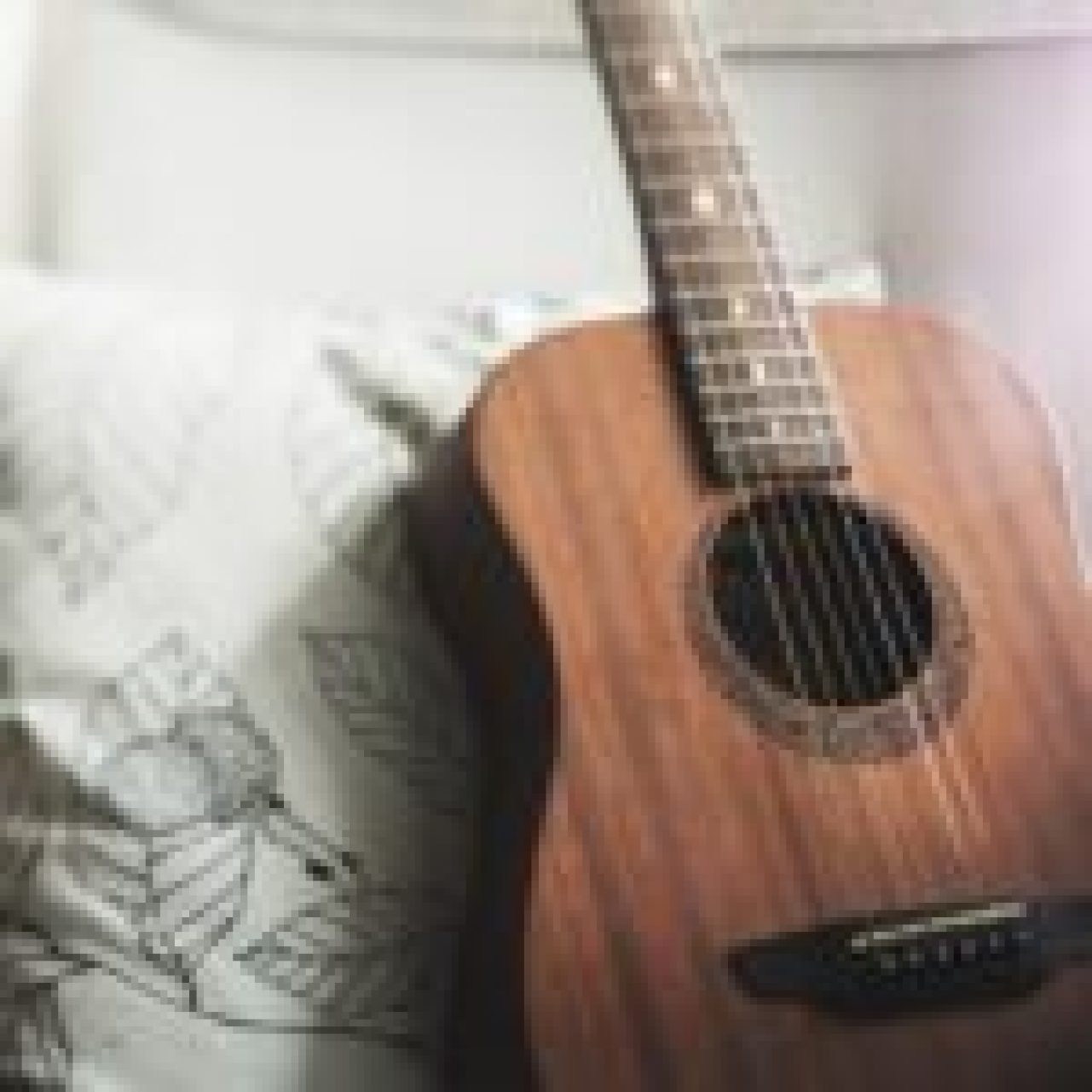 A close-up of an acoustic guitar with a wooden body and strings, highlighting the intricate details of the instrument.