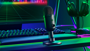 A high-quality streaming microphone on a desk setup with a colorful gaming background.