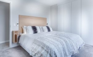 A cozy bedroom setup with a neatly made bed, showcasing a plush mattress and inviting pillows.