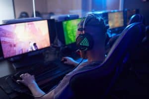A person wearing headphones and focused on a computer screen with multiple monitors.