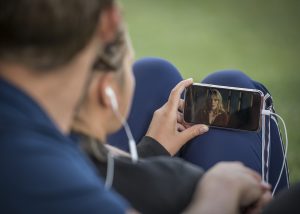 A person wearing headphones watches a video on their smartphone.