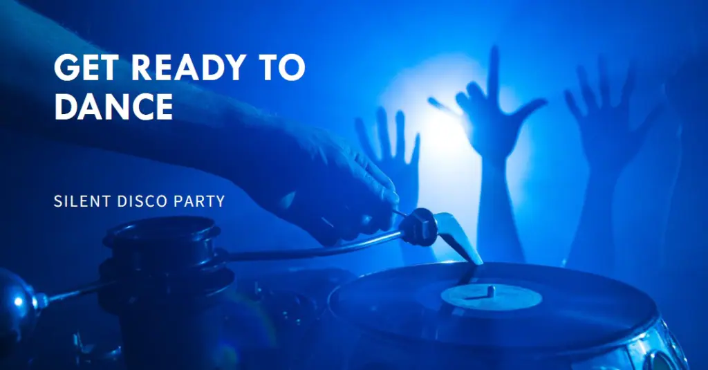 A DJ’s hand adjusting equipment at a silent disco party with raised hands in the background, illuminated by blue light.