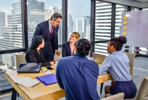 Group of five people having a meeting around a wooden table in a modern office with a cityscape view in the background. #DeFi
