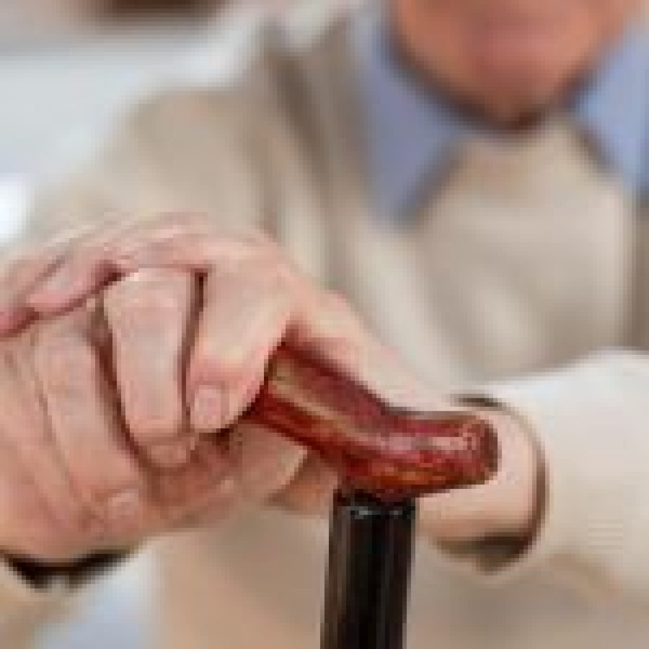 Close-up of an elderly person’s hands holding a wooden walking cane, symbolizing the need for support and stability. LoRa technology could enhance safety monitoring and assistance, improving their quality of life