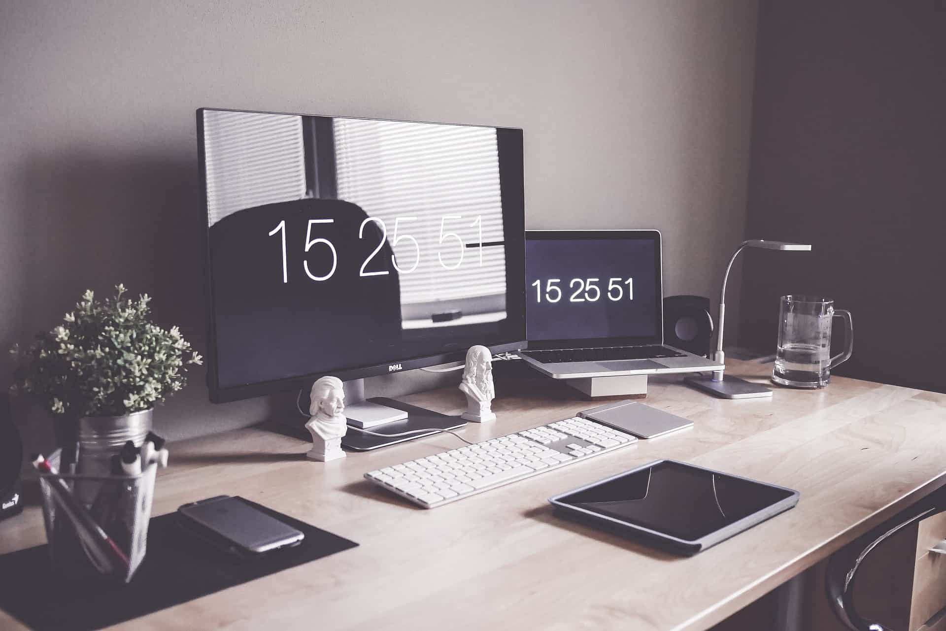 A well-organized desk with two monitors, a laptop, a tablet, headphones, and other accessories, representing a personalized and efficient home office setup. This image highlights the benefits of building your own PC, such as customization and tailored performance.