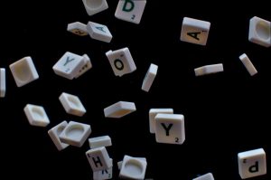 Scattered letter tiles from word games suspended in mid-air against a dark background #Unscrambling Tools