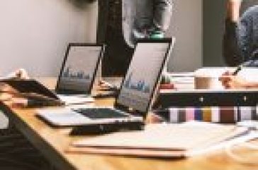 Professionals collaborating in an office with laptops displaying data graphs. #Technical Jobs