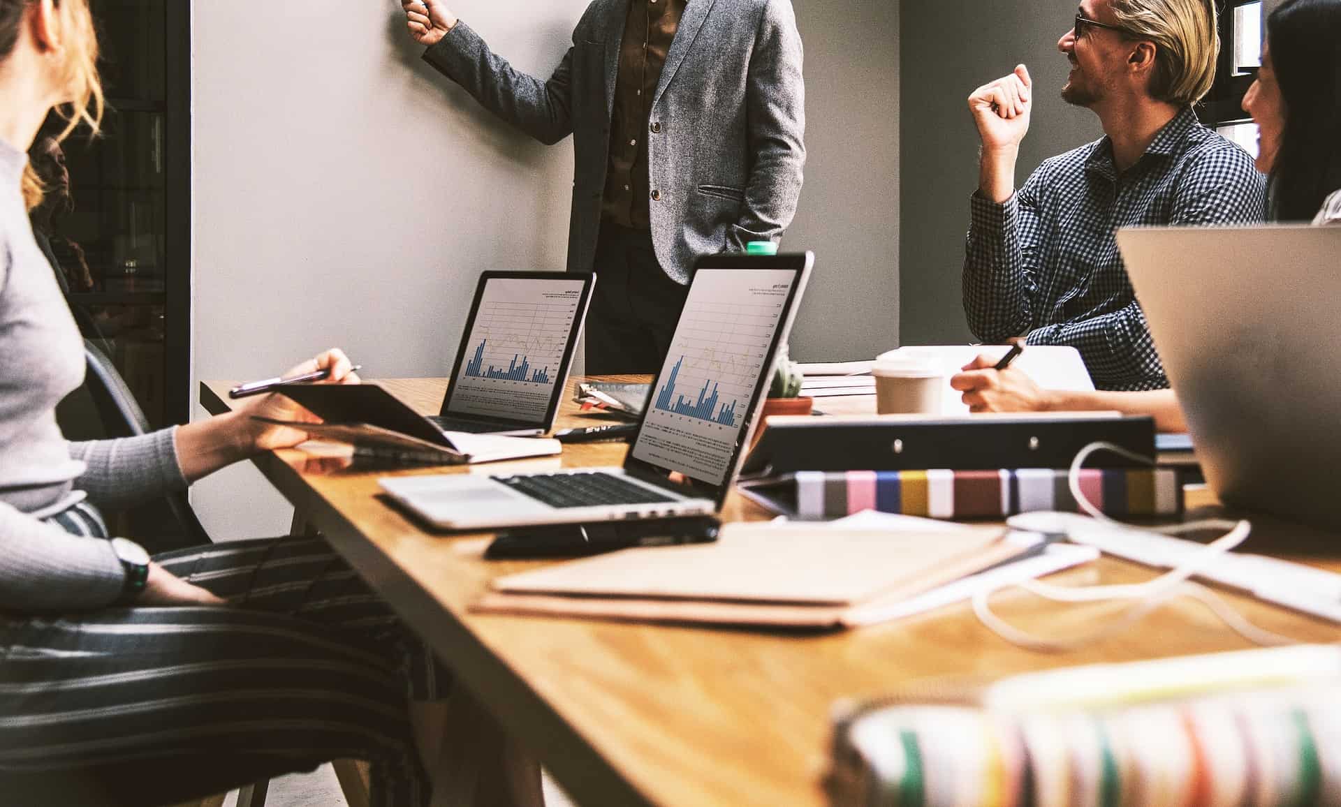 Professionals collaborating in an office with laptops displaying data graphs. #Technical Jobs