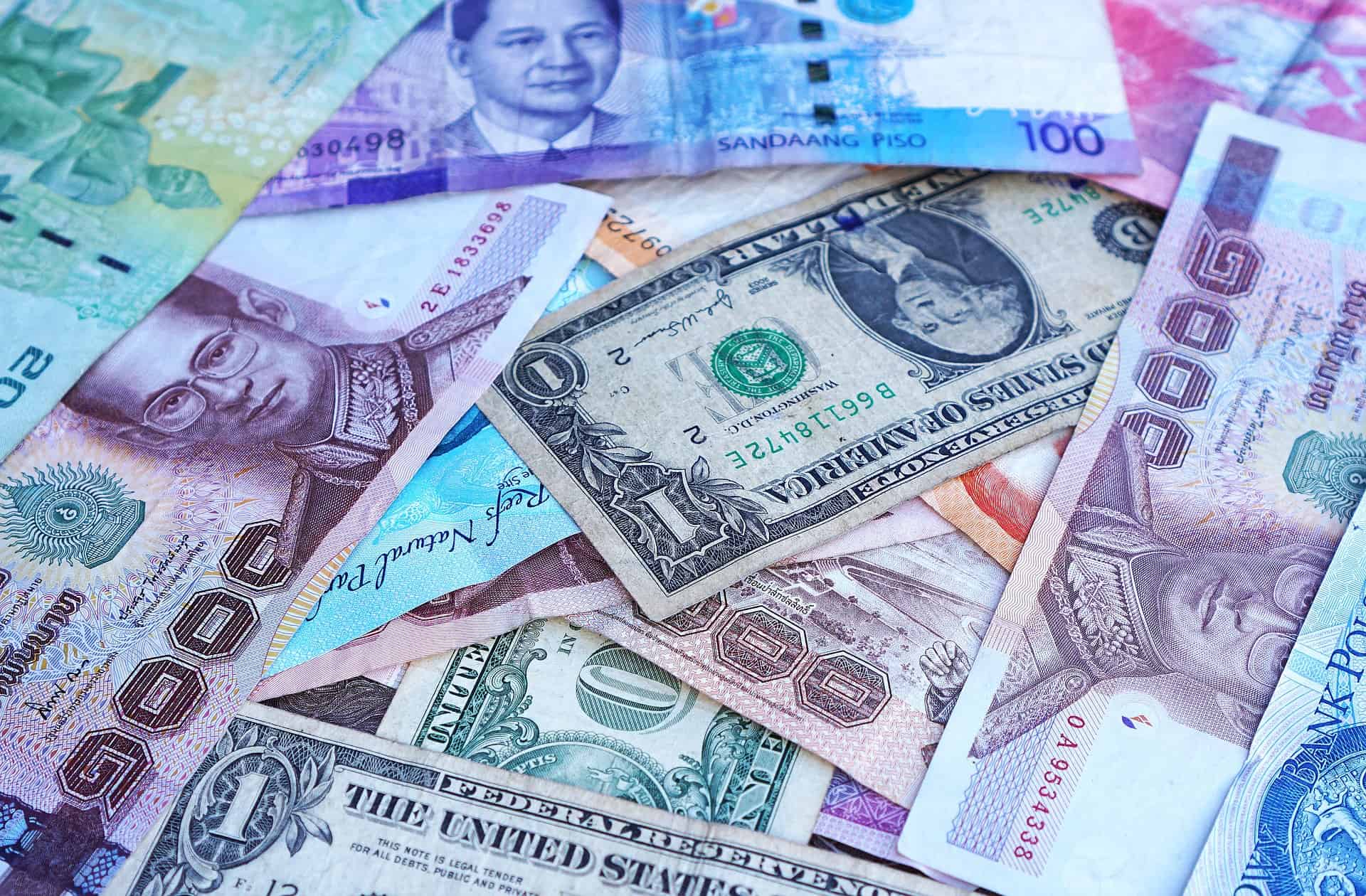 A variety of international banknotes including Singaporean dollars and US dollars spread out.
