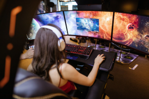 A gamer immersed in playing RuneScape 3 with multiple screens displaying cosmic graphics.