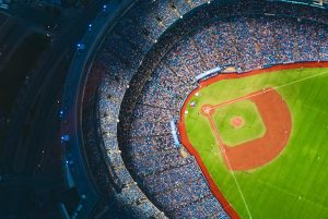 Aerial view of a packed baseball stadium during a night game, highlighting the vibrant atmosphere and community spirit of the sport.