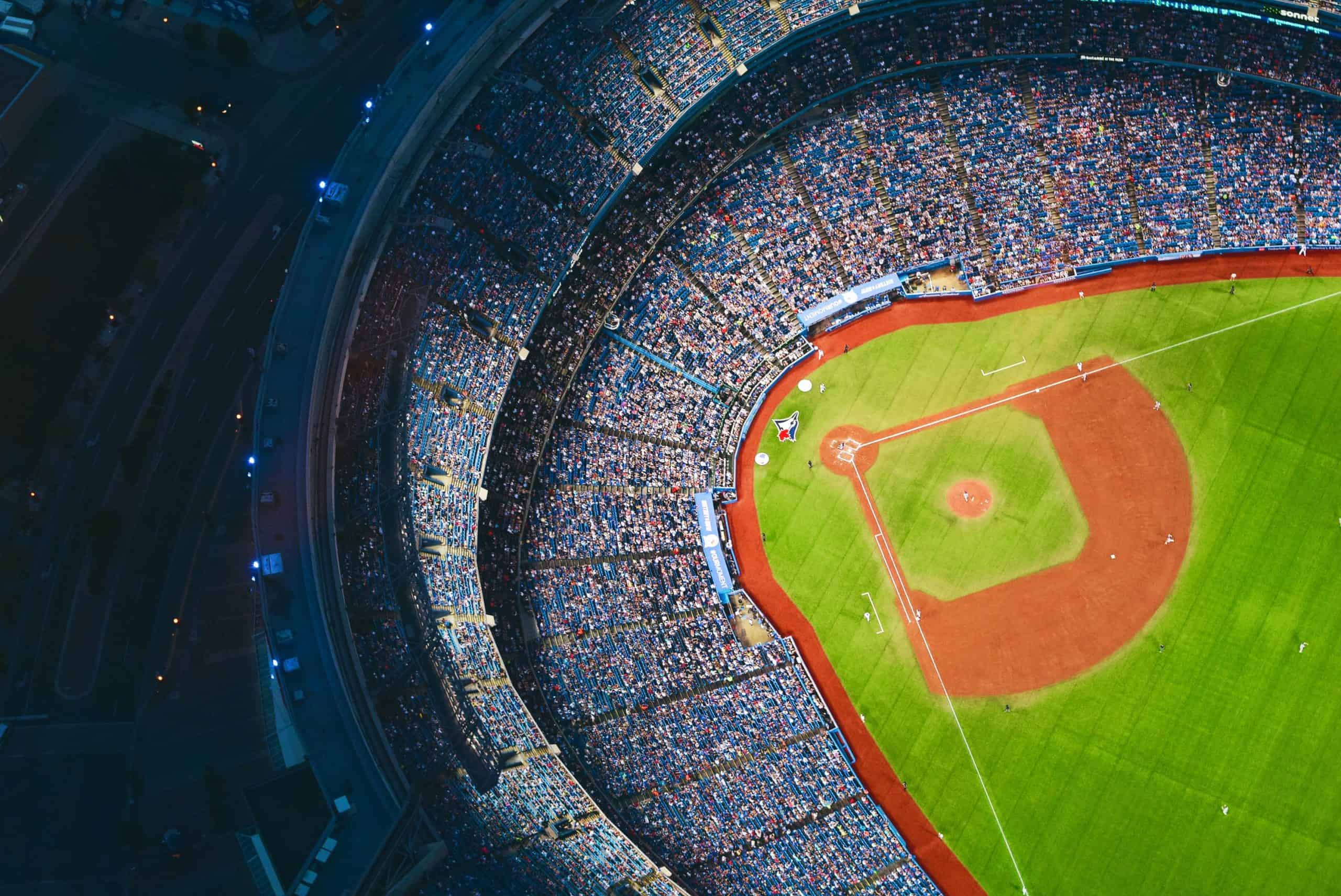 Aerial view of a packed baseball stadium during a night game, highlighting the vibrant atmosphere and community spirit of the sport.