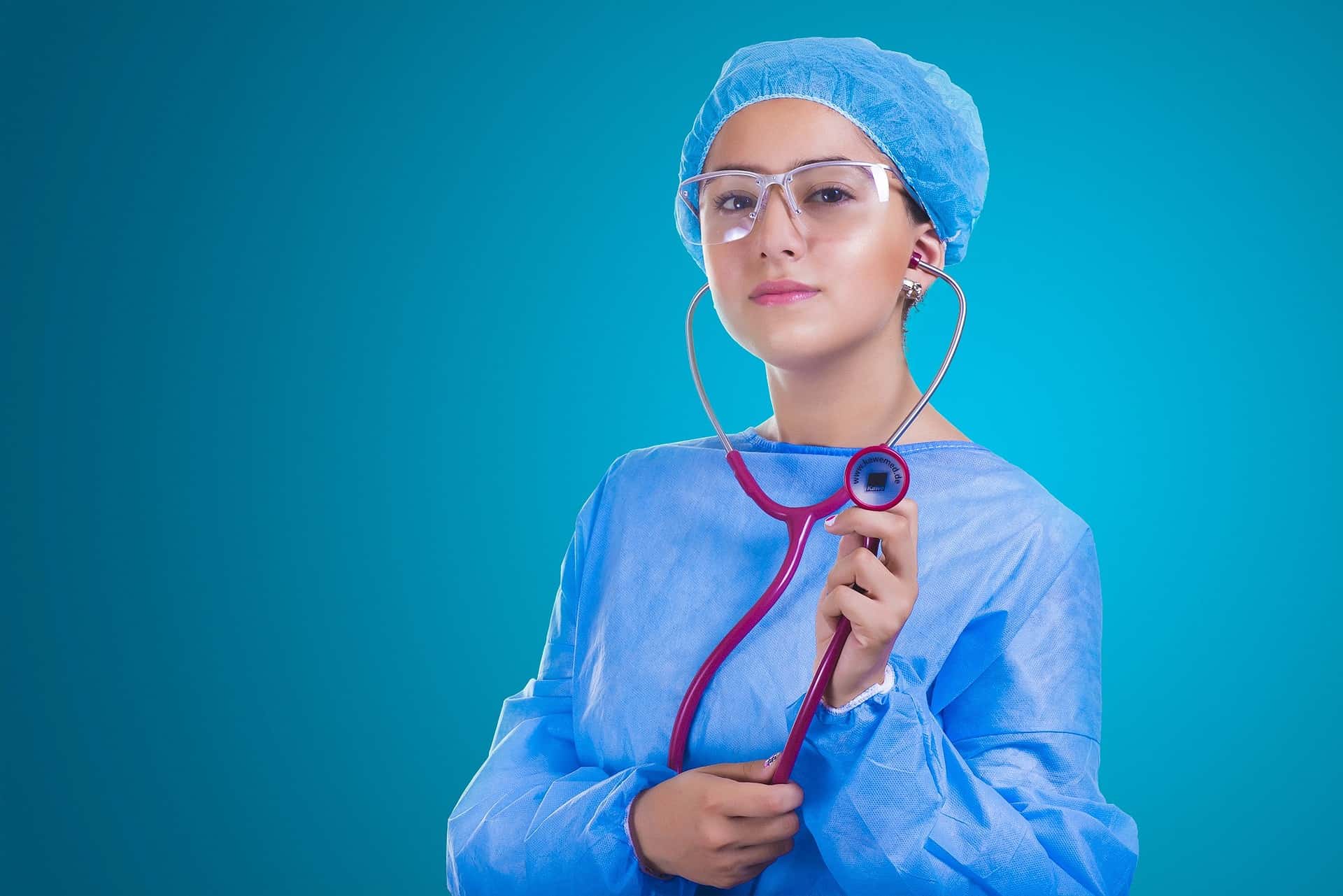 A healthcare professional in blue scrubs holding a red stethoscope, symbolizing readiness and expertise in the medical field.