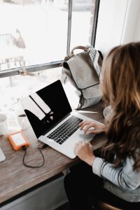 Professional writer working on a laptop at a wooden desk with an external hard drive connected, symbolizing focused documentation work.