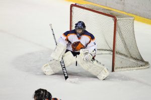 Hockey Protective Equipment -A hockey goalie in full gear, including a helmet, leg pads, blocker, and catcher, is positioned in front of the goal net during a game.