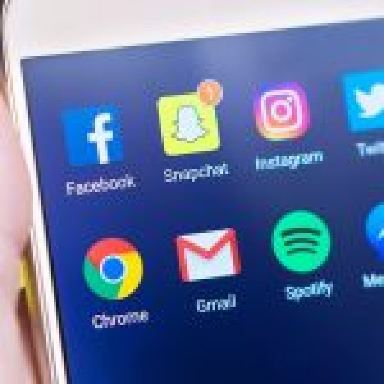 Smartphone screen displaying icons for Facebook, Snapchat, Instagram, Chrome, Gmail, Spotify and Messenger against a yellow background.