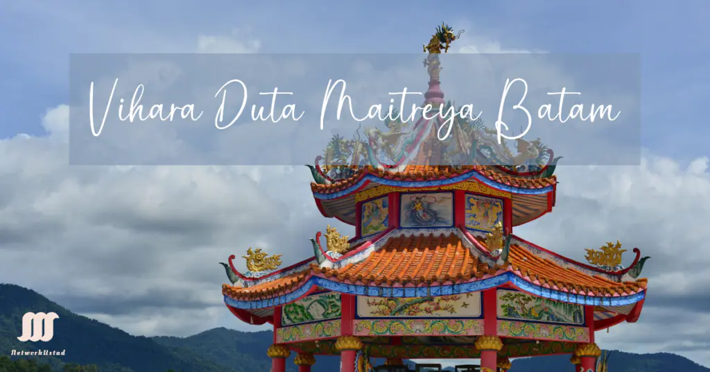A vibrant photograph showcasing the intricate architecture of Vihara Duta Maitreya Batam. The foreground features a traditional Chinese temple with elaborate roof designs, adorned with mythical creatures and colorful patterns. The background displays a serene sky filled with fluffy clouds over a mountainous landscape.