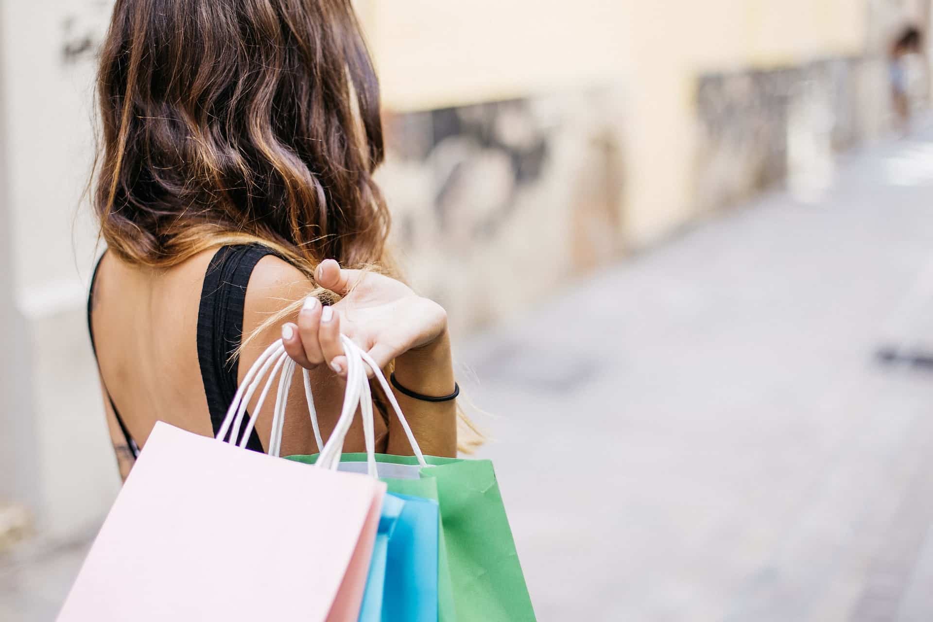 A shopper holding multiple colorful paper bags on a city street. #Salesforce