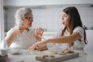 An elderly person and a young person baking together in a kitchen, illustrating the benefits of home care services.