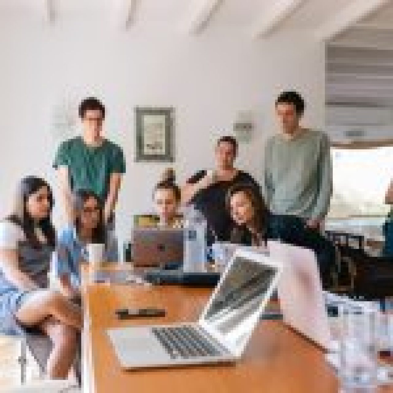 A group of diverse employees participating in a virtual team building activity via video conference, smiling and interacting with each other.