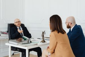 Three professionals discussing legal matters in an office setting with documents on the desk.