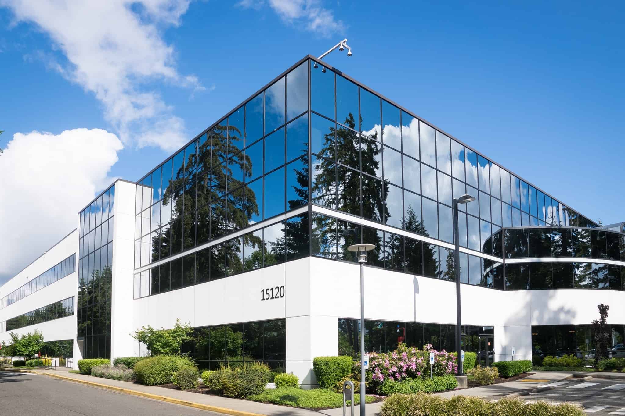 A modern two-story commercial building with reflective glass windows set against a backdrop of blue sky and greenery, symbolizing corporate success and effective public relations.