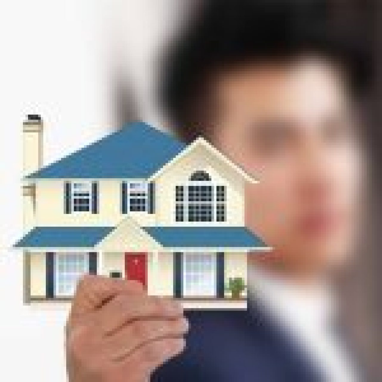 A hand holding a paper cut-out of a blue and white two-story house, symbolizing property investment.