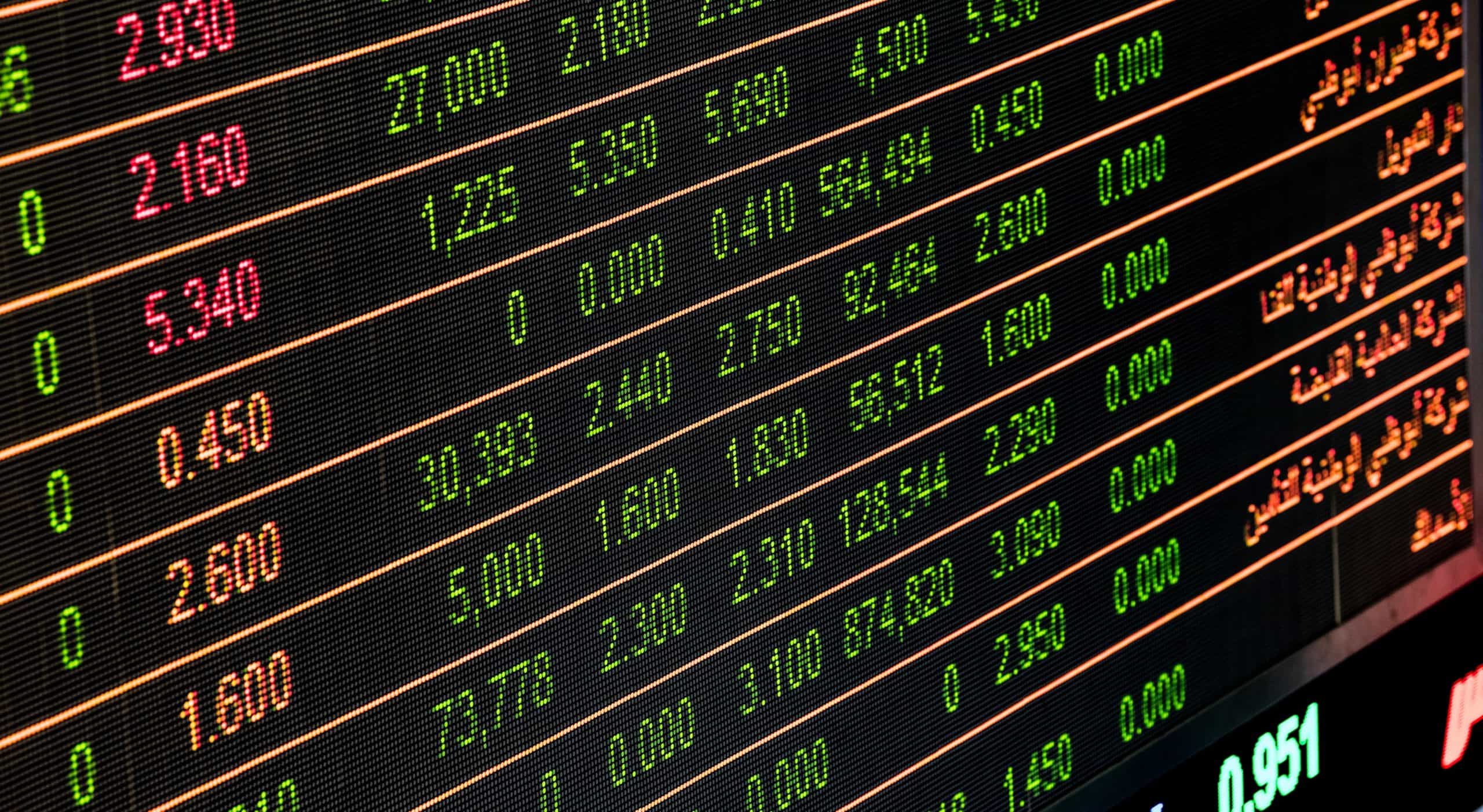 Electronic stock market display showing fluctuating share prices in red and green.