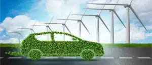 Green car made of foliage on a road with wind turbines in the background, symbolizing eco-friendly and sustainable transportation.