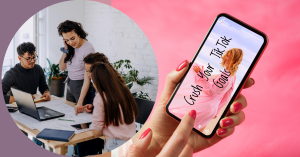 A person holding a smartphone with a TikTok post displayed, featuring a woman and the text ‘Crush your Fit Tok Goals,’ while in the background two individuals are working on laptops at a desk.