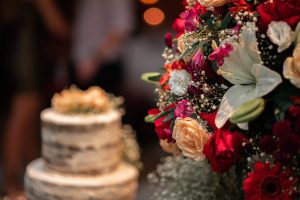 Close-up of a wedding cake and a vibrant floral arrangement, showcasing elegant and colorful wedding decor.