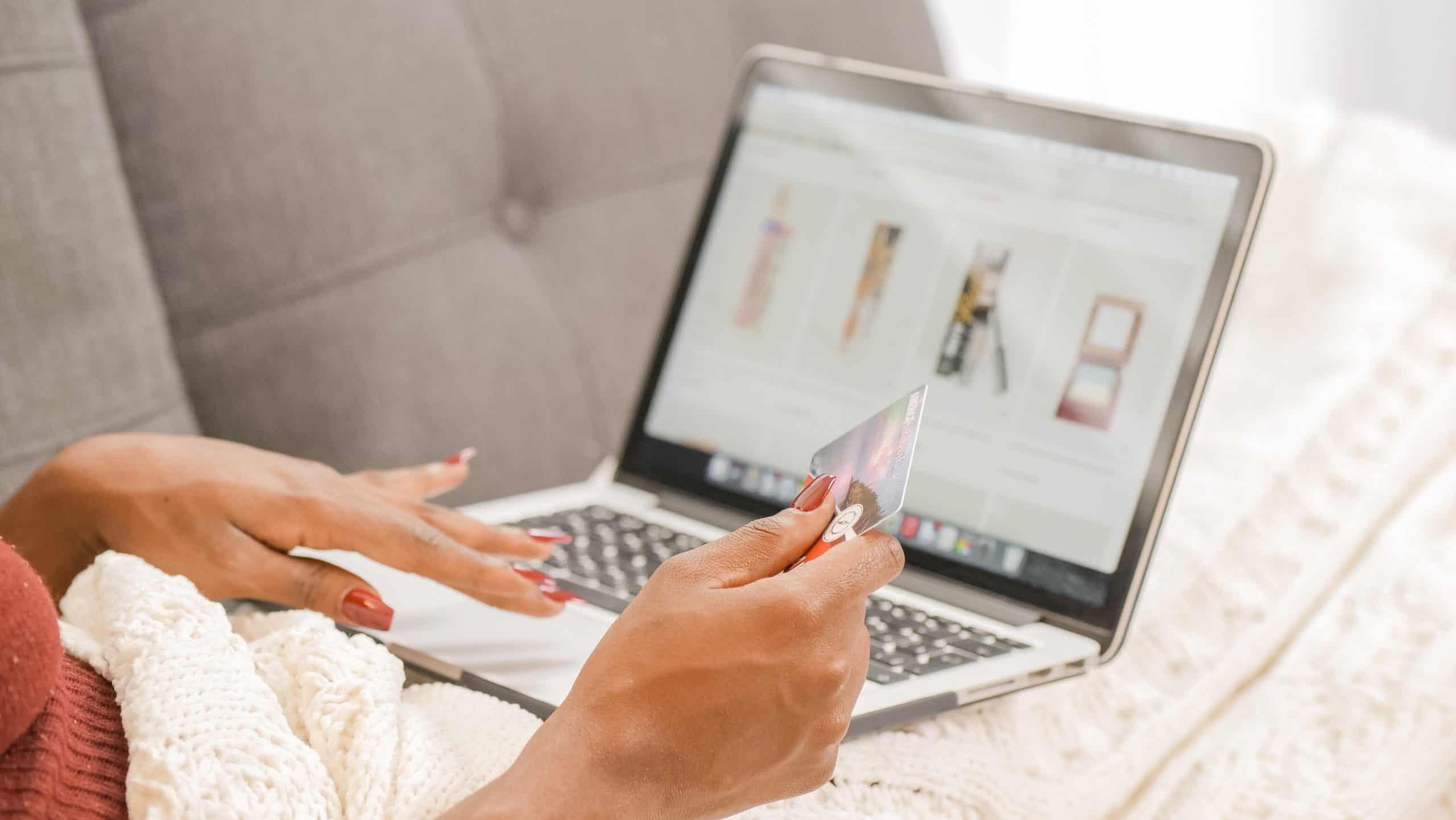 Person shopping online for eco-friendly products on a laptop while holding a credit card.