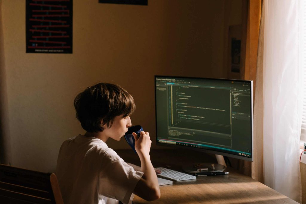A person working on computer coding while discussing over a mobile phone in a home office setup. #Google My Business Profile