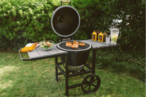 Outdoor barbecue grill with chicken, salad, sauces, and lemonade.