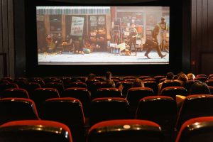 A vibrant movie scene projected on a big screen in an empty theater with rows of red seats, symbolizing high-quality cinematic experiences available through MKVCinema.