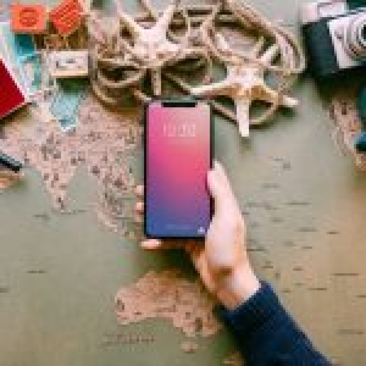 A traveler’s hand holding a smartphone over a world map surrounded by travel essentials like passport, camera, and currency.