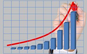 Hand drawing an ascending red trend line on a bar graph indicating positive growth.