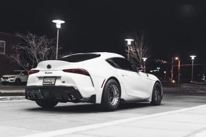 Rear view of a white Toyota Supra MK4 parked under streetlights at night.