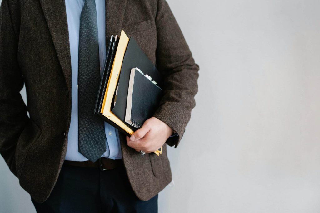 A professional dressed in formal attire holding a stack of books, symbolizing academic expertise.