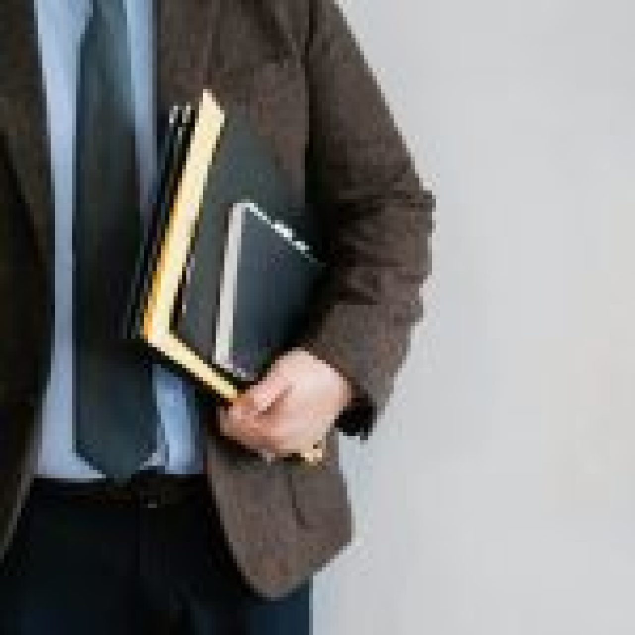 A professional dressed in formal attire holding a stack of books, symbolizing academic expertise.